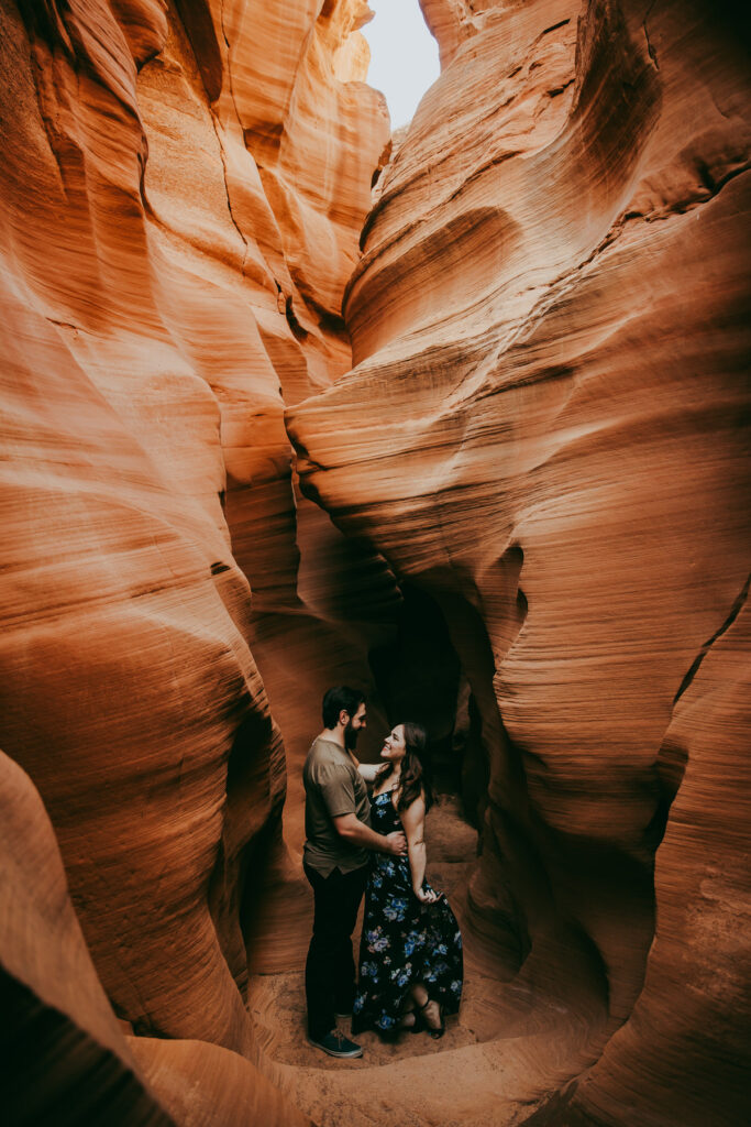 a man and woman in a dress hold each other in Secret Antelope Canyon.
