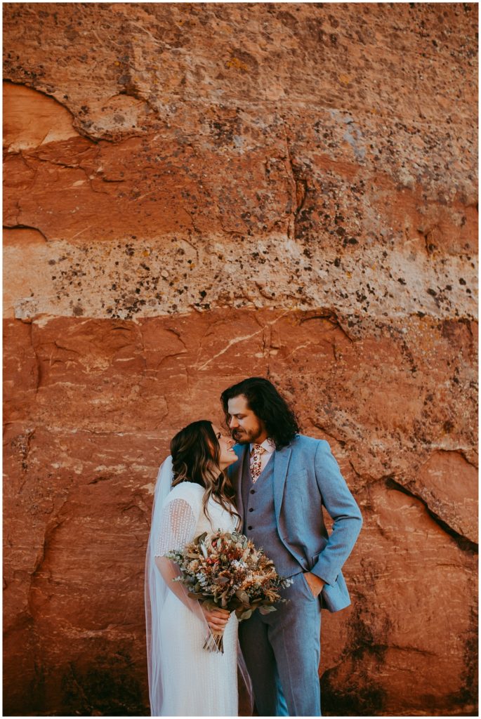 bride and groom look into each other's eyes in front of red rocks at Cathedral Rock