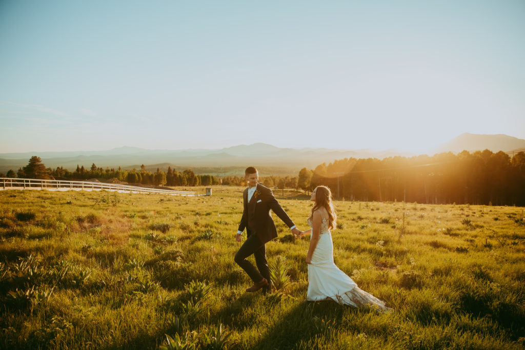 bride and groom walk through a field outside of Flagstaff Arizona