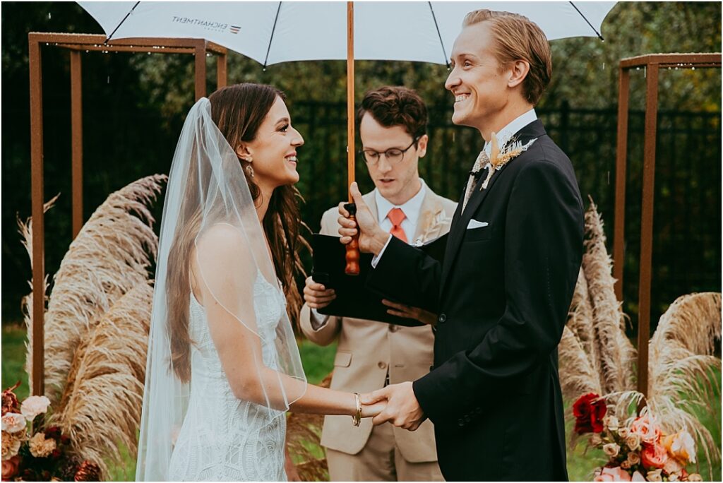 groom holds umbrella above bride during Sedona wedding ceremony 