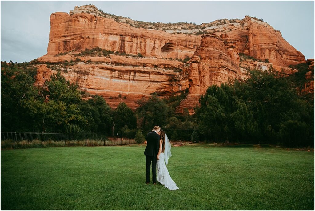bride and groom kiss beneath iconic Sedona red rocks at Enchantment Resort