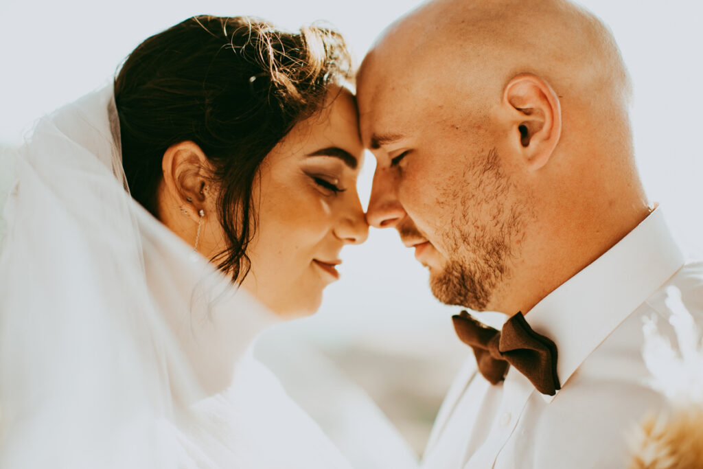 a tightly cropped photo of a bride and groom touching foreheads with their eyes closed