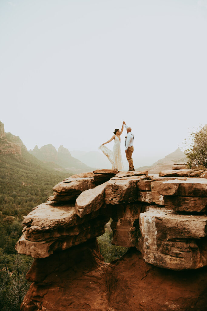 a groom spins his bride on top of Merry Go Round Rock in Sedona