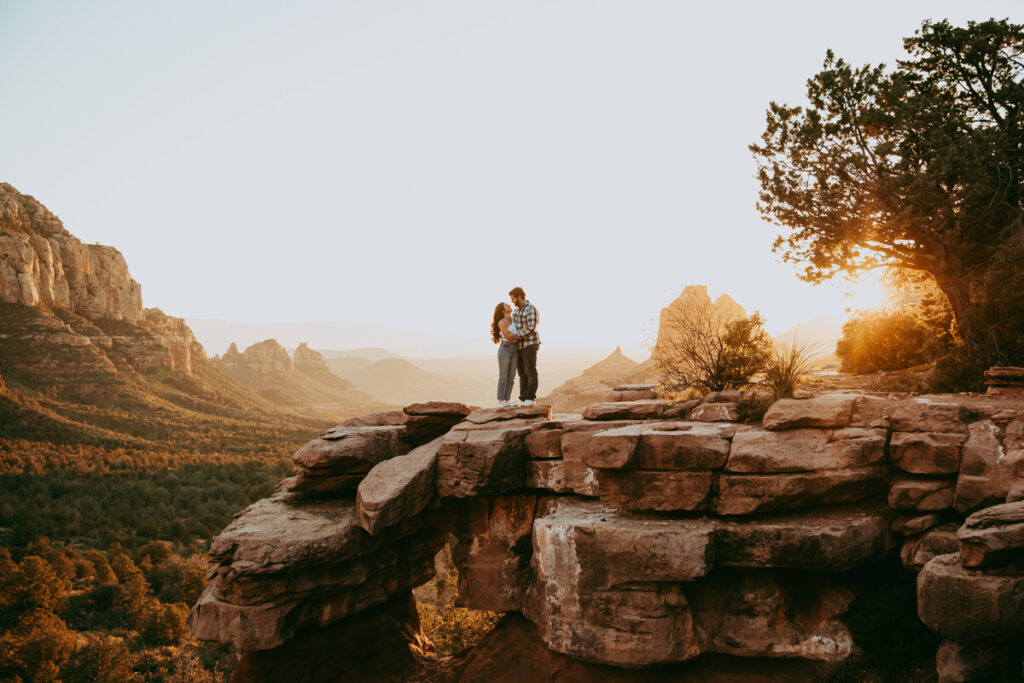 A couple holds each other at Merry Go Round Rock during sunset for their Sedona engagement photos