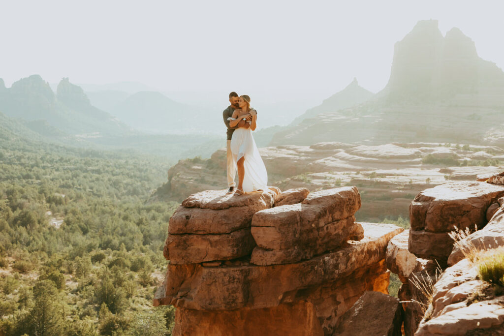 A couple holds each other at Merry Go Round Rock during sunset for their Sedona engagement photos