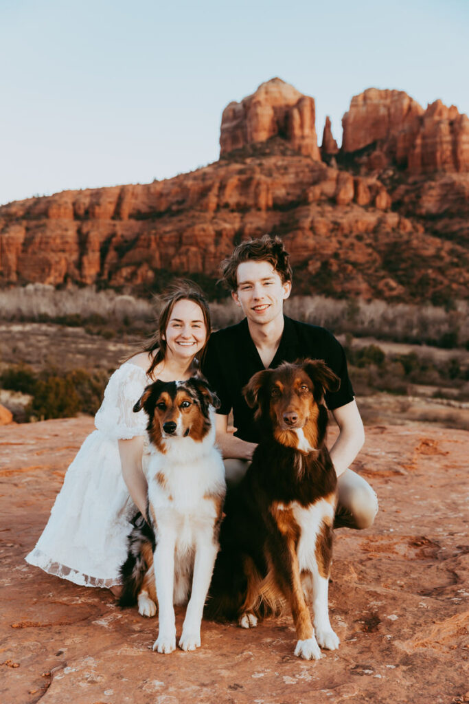 a man and woman pose with their two cute dogs during their sedona engagement photos
