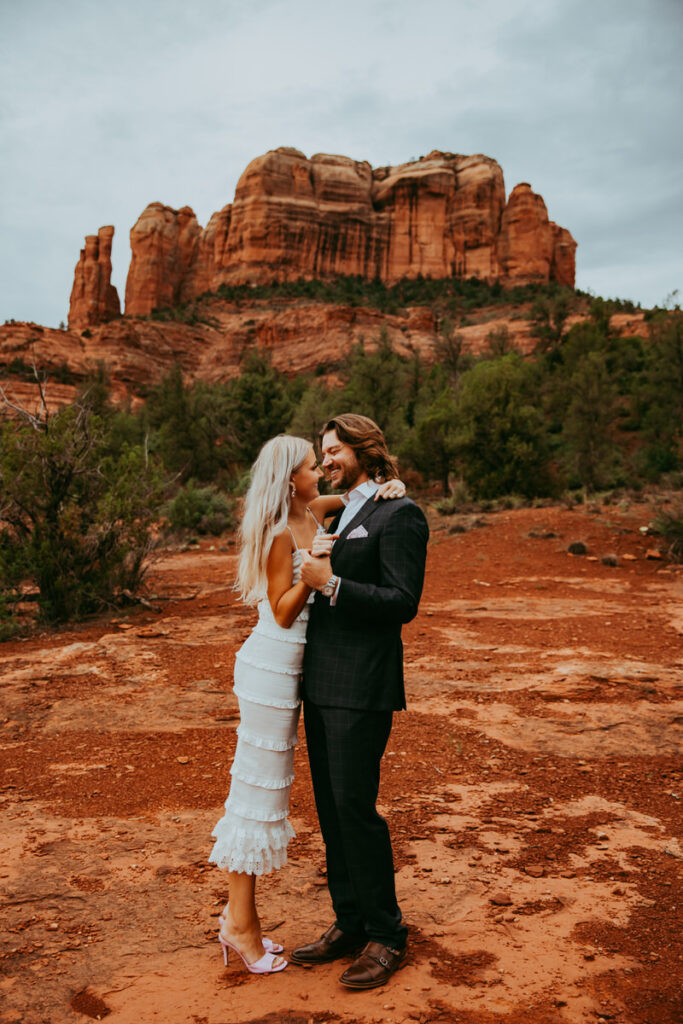 man and woman stand together holding hands in sedona arizona for their engagement photos
