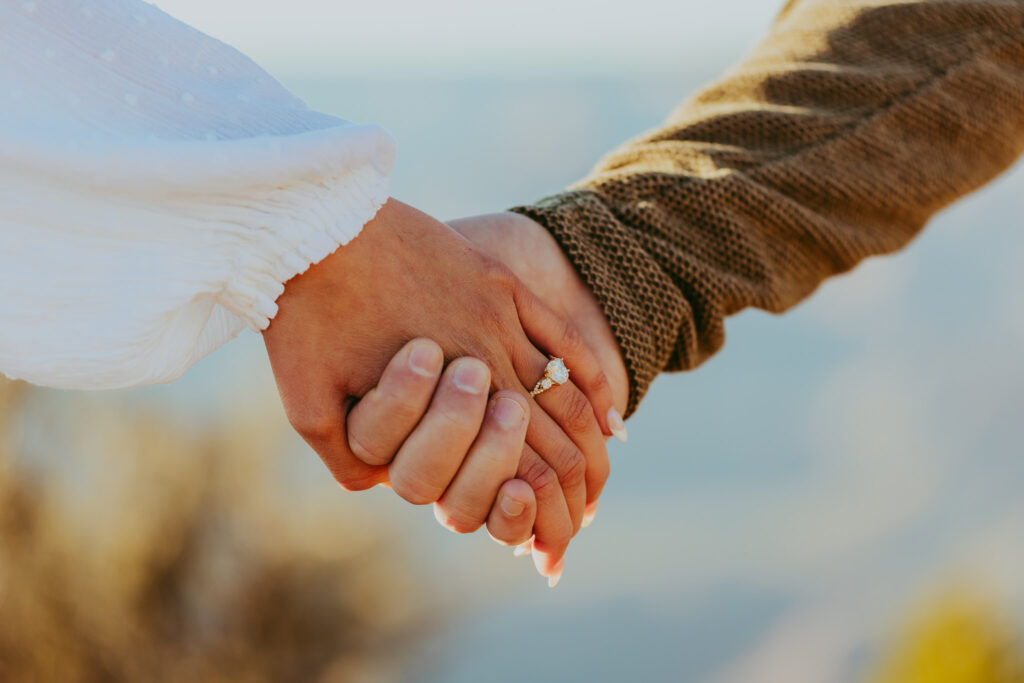 man holds and woman's hand with a wedding ring on her finger