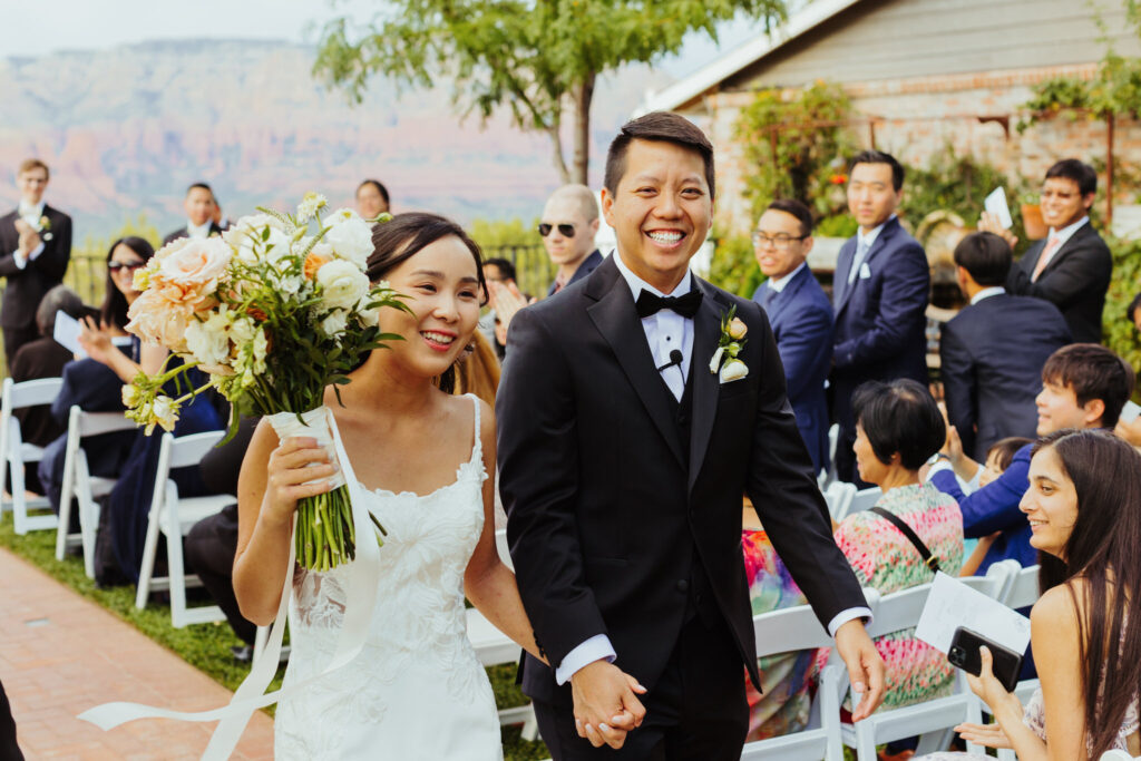 beautiful bride and groom smile as they walk down the aisle after getting married at sky ranch lodge