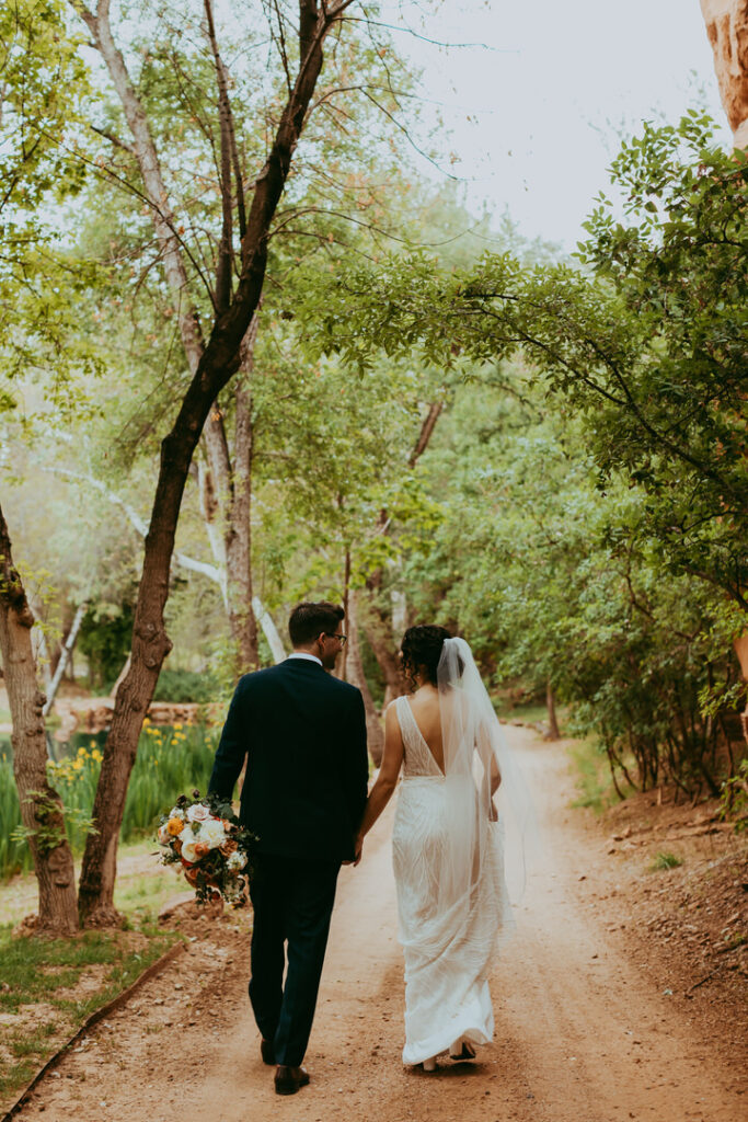 bride and groom walking down a dirt road holding hands