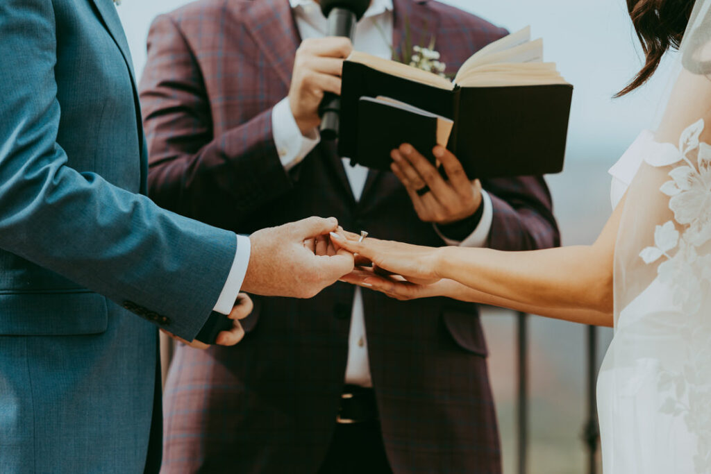 groom placing the ring on brides finger