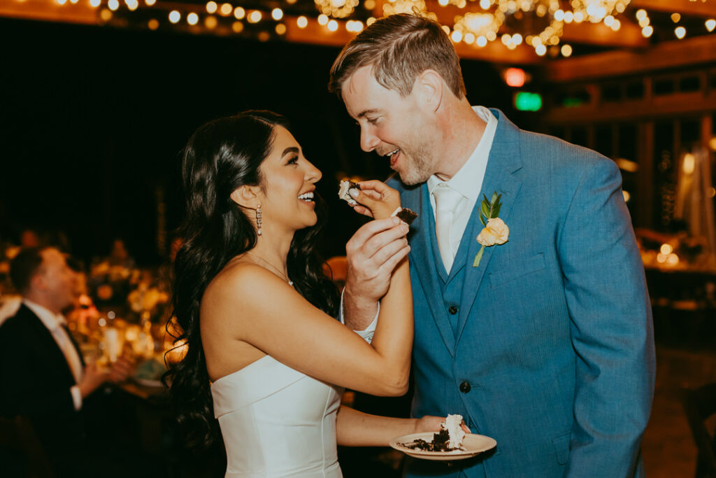 bride and groom share wedding cake at wedding at Sky Ranch Lodge